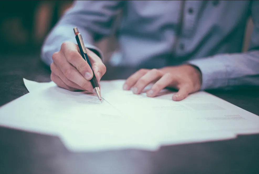 Mains d'une personne remplissant des documents administratifs pour l'accompagnement des familles.